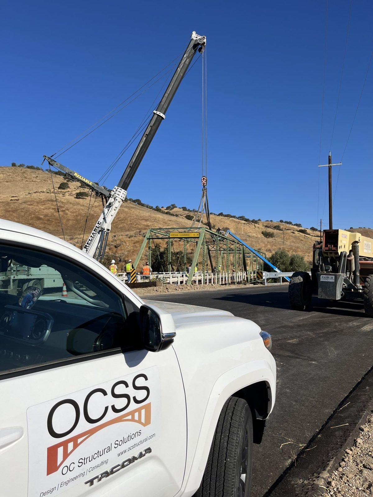OCSS truck on site as a crane lifts a steel truss span